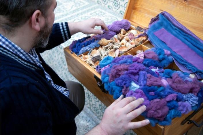 Mouhamad Ghassen Nouira looks at samples of his dyed fabrics and yarn placed in a box.