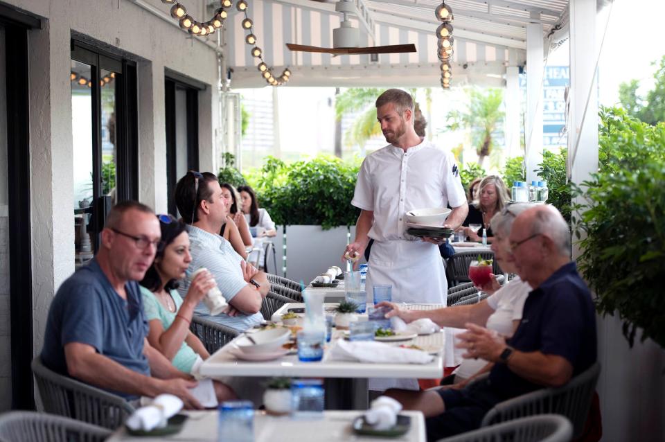 Server Alex Woodward talks to patrons at the new AquaGrille restaurant in Juno Beach on June 2.