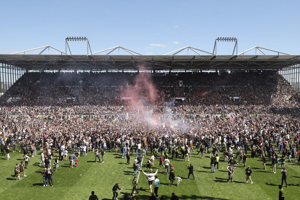 St. Pauli's fans invade the field after their team won 3-1 during a second division Bundesliga soccer match between St. Pauli and VfL Osnabrück, at the Millerntor Stadium, in Hamburg, Germany, Sunday, May 12, 2024. (Christian Charisius/dpa via AP)