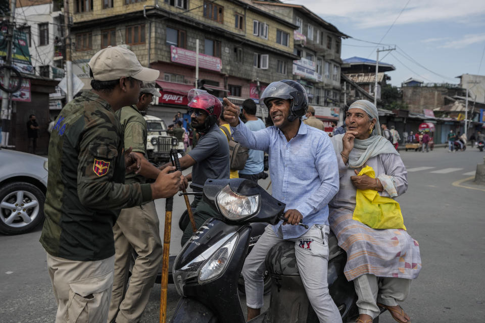 Kashmiri motorists seek permission from policemen to cross a road near a checkpoint during restrictions in Srinagar, Indian controlled Kashmir, Sunday, Aug. 7, 2022. Authorities had imposed restrictions in parts of Srinagar, the region's main city, to prevent gatherings marking Muharram from developing into anti-India protests. (AP Photo/Mukhtar Khan)