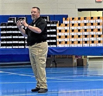 Holmes County Sheriff's Office Deputy Sgt. Joe Mullet spoke about bike safety at the assembly last week at Chestnut Ridge. Behind Mullet were the more than 200 bike helmets donated by Pomerene Hospital.