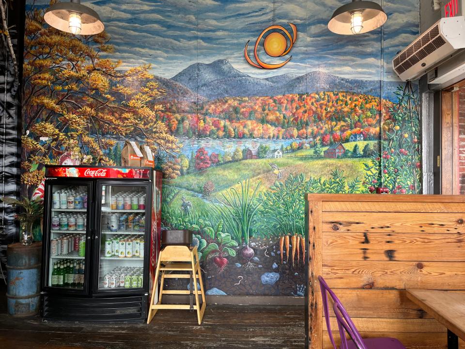 Pingala's Vermont farm scene by T. Ariel Goreau is on the large wall at the entrance to the cafe. It depicts a fall farm scene with fall foliage, snowy mountain tops and root vegetables growing.