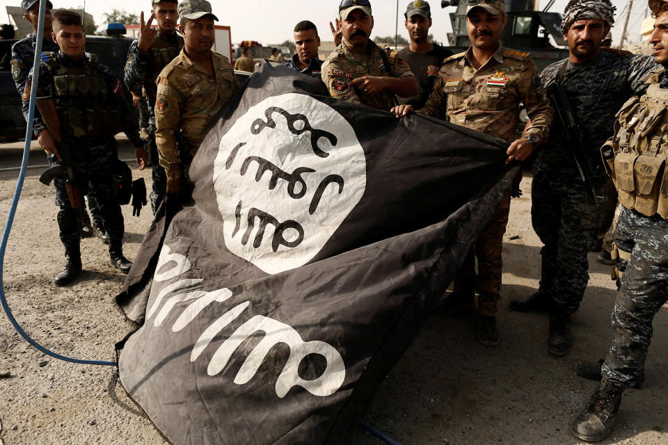 Iraqi soldiers pose with the Islamic State flag