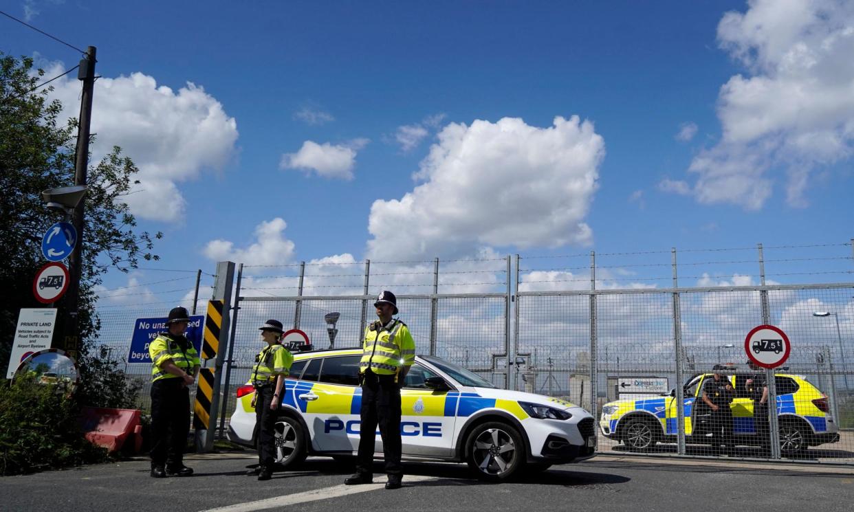 <span>Police officers guarding the access road to the Brook House IRC at Gatwick airport, June 2022.</span><span>Photograph: Niklas Halle’n/AFP/Getty Images</span>