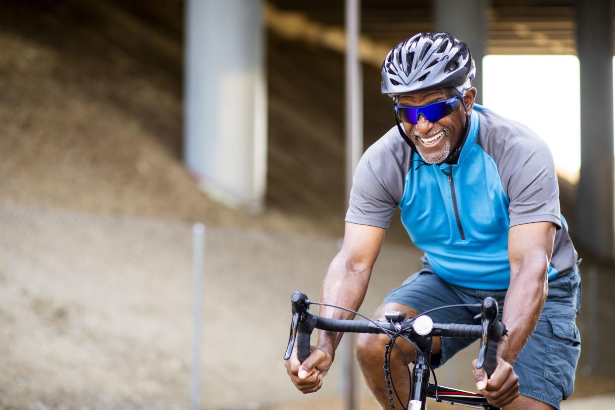 A senior black man rides a road bike on a trail for exercise.