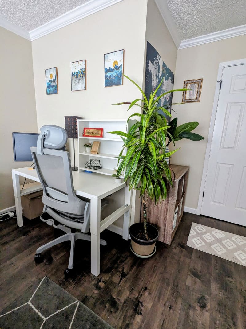 Beige workspace area in bedroom with white desk, office chair, and artwork