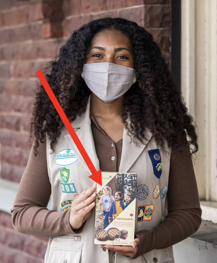 Girl Scout in uniform holding a box of Adventurefuls cookies