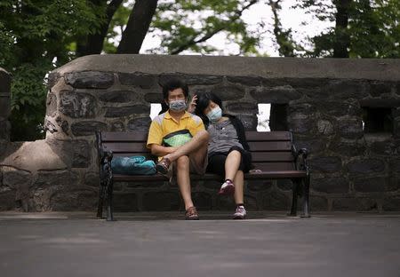 A couple wearing masks to prevent contracting Middle East Respiratory Syndrome (MERS), rests at "N Seoul Tower" located atop Mt. Namsan in Seoul, South Korea, June 8, 2015. REUTERS/Kim Hong-Ji