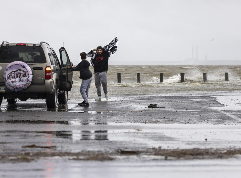 A pair of passersby can't decide whether to approach the waters of the Potomac River as Tropical Storm Ophelia creates waves next to Wilkerson's Seafood Restaurant along McKinney Boulevard in Colonial Beach, Va., on Saturday, Sept. 23, 2023. (Peter Cihelka/The Free Lance-Star via AP)