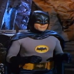 Adam Wests Batman in his full Batsuit with the iconic yellow emblem and black bat symbol