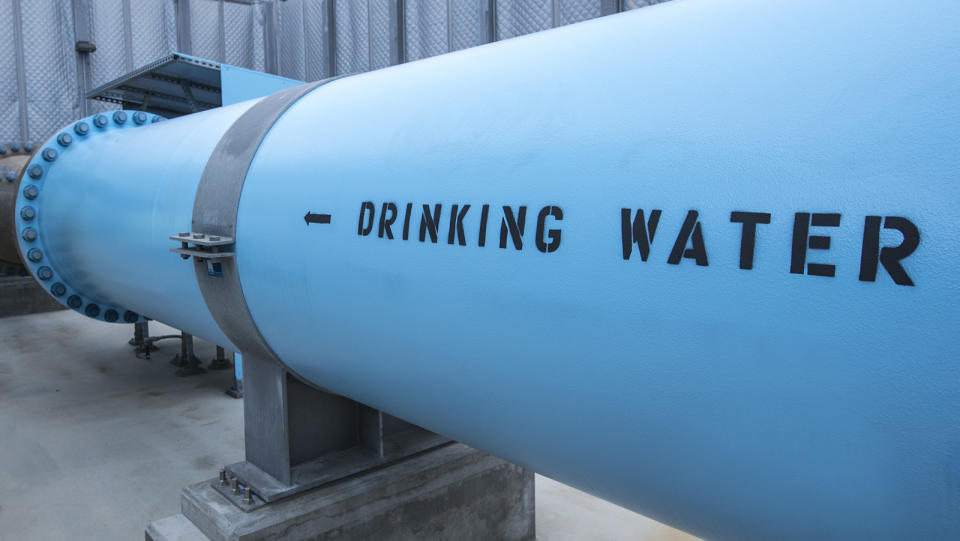 Drinking water exits a desalination plant in a large, blue pipe