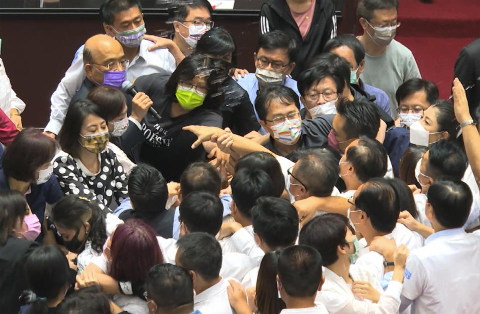 In this image taken from video by Taiwan's EBC, Premier Su Tseng-chang, in purple mask, tries to make a policy speech amid a scuffle between opposition Nationalist party and ruling Democratic Progressive Party lawmakersduring a parliament session in Taipei, Taiwan, Tuesday, Sept. 28, 2021. Taiwan's legislature on Tuesday descended into a rowdy brawl on Tuesday, after opposition lawmakers interrupted an important policy address and rushed the podium. (EBC via AP )