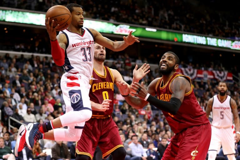 Trey Burke of the Washington Wizards looks to make a pass in front of Kyrie Irving (R) of the Cleveland Cavaliers at Verizon Center