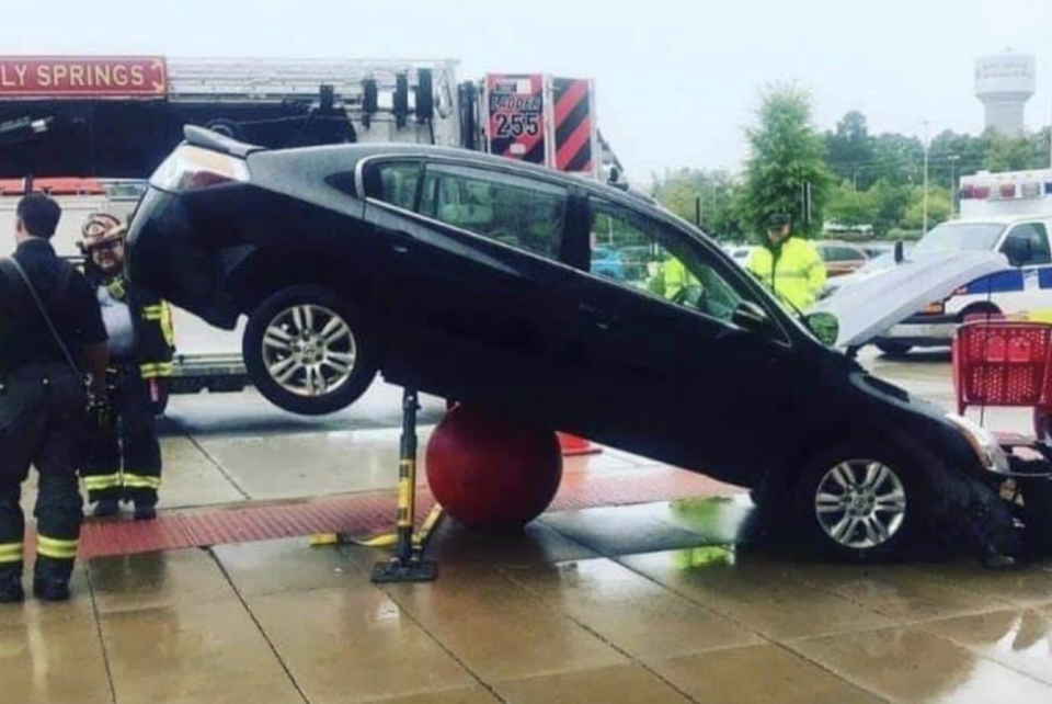 A car parked on top of a concrete bollard outside of Holly Springs Target.