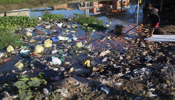 <p>A boy reaches for a ball along a polluted canal in the Mare favela community complex on July 18, 2016 in Rio de Janeiro, Brazil. Polluted canals in Rio such as this one empty in Guanabara Bay. The Mare complex is one of the largest favela complexes in Rio and is challenged by violence, pollution and poverty. The Rio 2016 Olympic Games begin August 5. (Mario Tama/Getty Images)