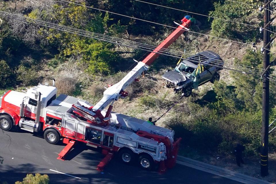 Workers move a vehicle after a rollover accident involving golfer Tiger Woods Tuesday, Feb. 23, 2021, in Rancho Palos Verdes, Calif., a suburb of Los Angeles.