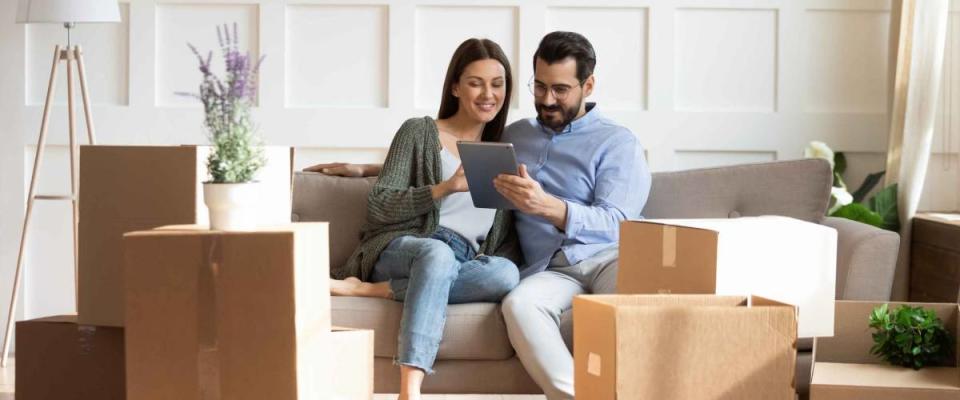 Full length happy family sitting on couch among cardboard