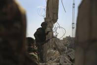 Kurdish-led Syrian Democratic Forces fighters, take their positions at the defense wall of Gweiran Prison, in Hassakeh, northeast Syria, Sunday, Jan. 23, 2022. Clashes between U.S.-backed Syrian Kurdish fighters and militants continued for a fourth day Sunday near a prison in northeastern Syria that houses thousands of members of the Islamic State group, the Kurdish force said. (AP Photo/Hogir Al Abdo)