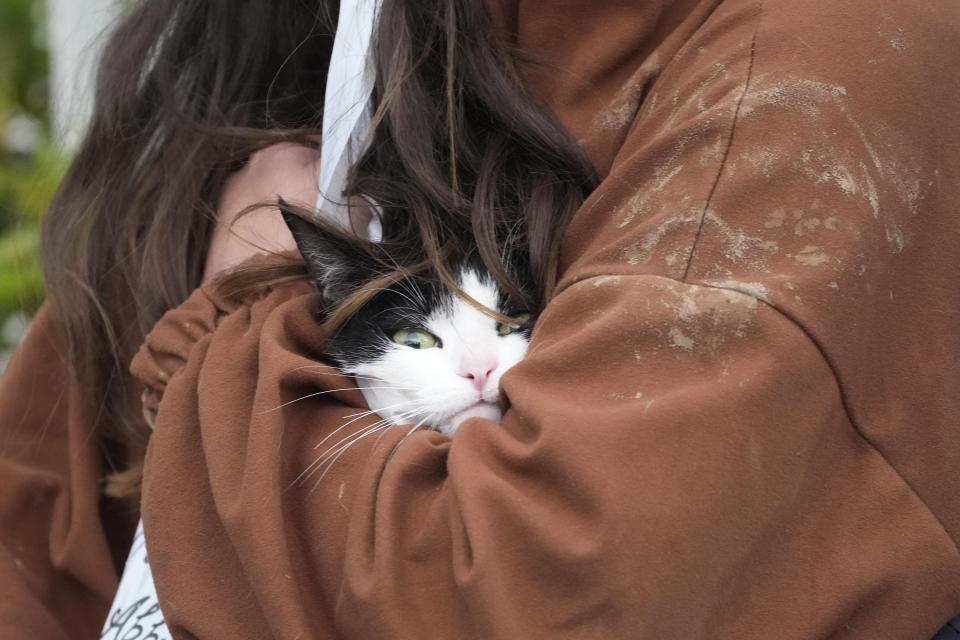 A woman hugs her rescued cat in Campi di Bisenzio, in the central Italian Tuscany region, Friday, Nov. 3, 2023. Record-breaking rain provoked floods in a vast swath of Tuscany as storm Ciaran pushed into Italy overnight Friday, trapping people in their homes, inundating hospitals and overturning cars. At least three people were killed, and four were missing. (AP Photo/Gregorio Borgia)