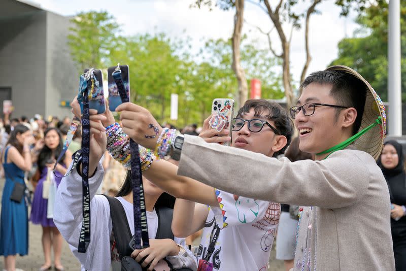 Taylor Swift's fans from Vietnam take a picture of their concert passes at the National Stadium during Swift's Eras Tour concert in Singapore