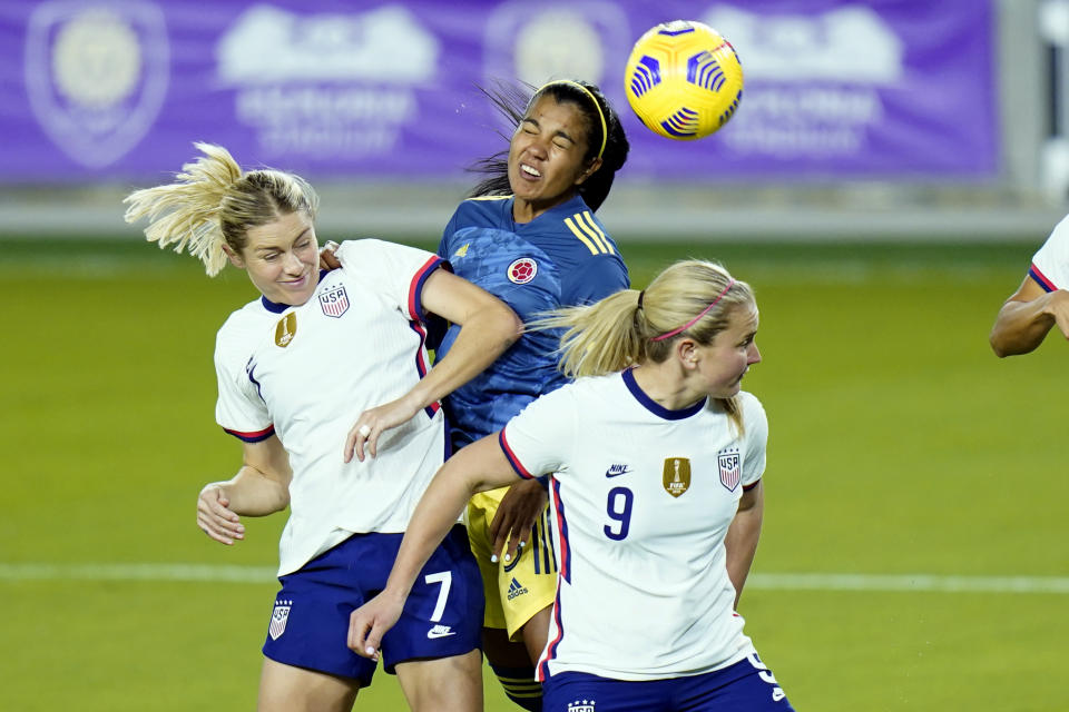 Colombia defender Daniela Arias, center, tries to head the ball to the goal off a corner kick as she is defended by United States defender Abby Dahlkemper (7) and midfielder Lindsey Horan (9) during the first half of an international friendly soccer match, Monday, Jan. 18, 2021, in Orlando, Fla. (AP Photo/John Raoux)