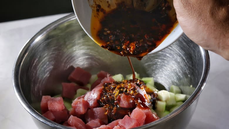 pouring sauce into bowl of tuna