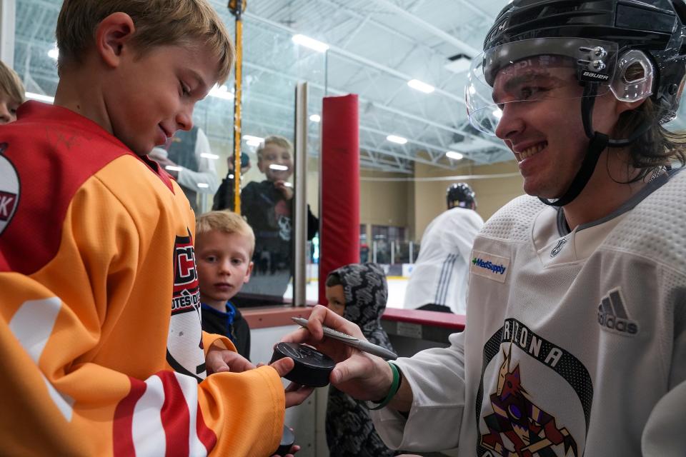 Coyotes forward Clayton Keller (9), at right, signs autographs for fans during an open practice at Ice Den Scottsdale on Saturday, Nov. 19, 2022, in Scottsdale.