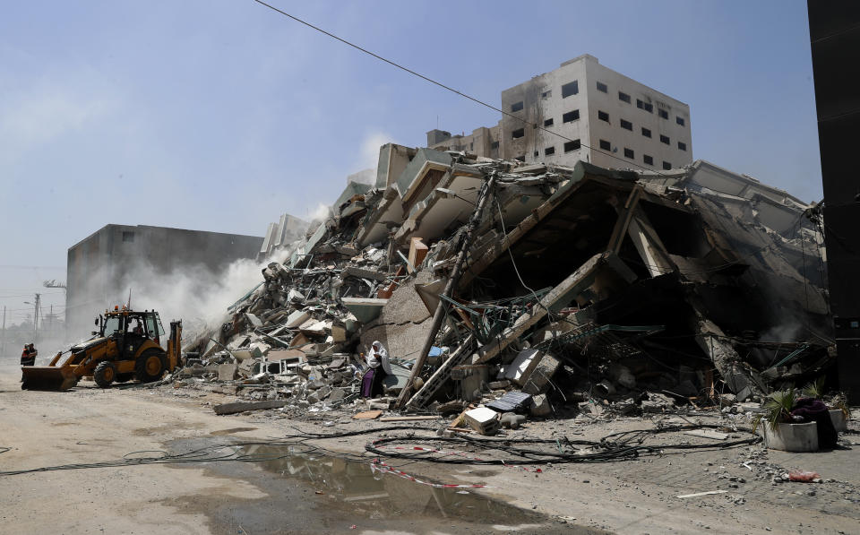 Workers clear the rubble of a building that was destroyed by an Israeli airstrike on Saturday, that housed The Associated Press, broadcaster Al-Jazeera and other media outlets, in Gaza City, Sunday, May 16, 2021. (AP Photo/Adel Hana)