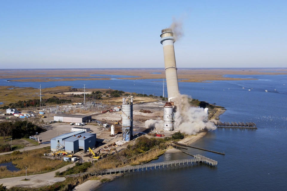 The smokestack at the former B.L. England Generating Station, a coal and oil burning power plant in Upper Township, N.J., is toppled during a control demolition on Thursday, October 26, 2023. The site will be redeveloped as a mixed-use residential and commercial project, and a nearby electrical substation will be used to connect New Jersey's soon-to-come offshore wind farms with the electrical grid. (AP Photo/Ted Shaffrey)