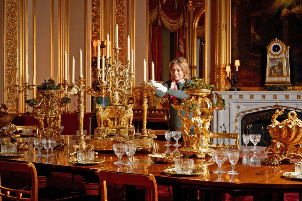 For single use only in relation to the Christmas displays at Windsor Castle in 2020, not to be archived, sold on or used out of context. Undated handout photo issued by the Royal Collection Trust of a sRoyal Collection Trust curator puts the finishing touches on a special display of the silver-gilt Grand Service in the State Dining Room at Windsor Castle.