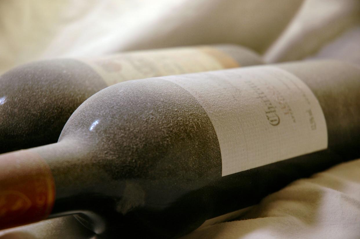 Close-up of two dusty wine bottles covered that look as if they have been sitting in a cellar for many years.