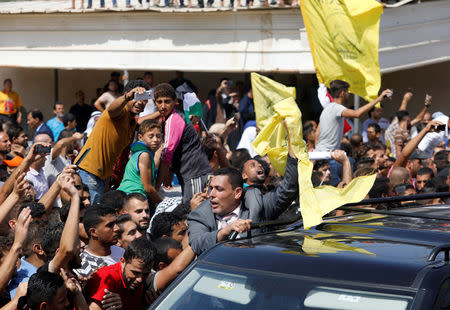 People celebrate as the convoy of Palestinian Prime Minister Rami Hamdallah arrives to take control of Gaza from the Islamist Hamas group, in the northern Gaza Strip October 2, 2017. REUTERS/Suhaib Salem