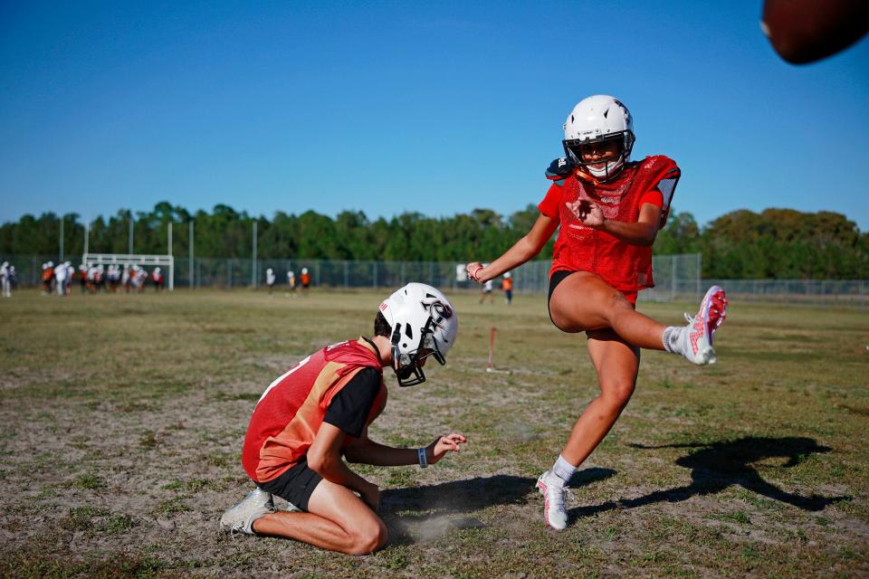 Gaby Rourke practices kicking as Camden Michaud holds during Thursday's football practice at Atlantic Coast High School in Jacksonville. Rourke, a 17-year-old high school junior, became the first female varsity football player in school history this season. Rourke, a four-sport varsity athlete, is a goalkeeper and defender in girls soccer, wide receiver in girls flag football, middle blocker in girls volleyball and place kicker on the varsity football team.