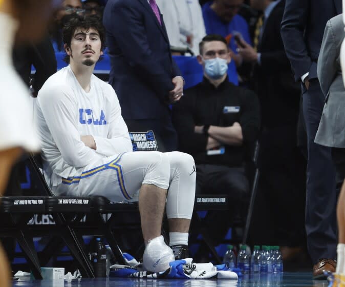 UCLA's Jaime Jaquez Jr. sits on the bench with ice on his ankle after leaving the court with an injury March 19, 2022.