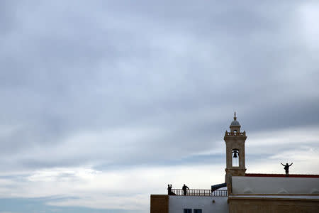 People take pictures next to the bell tower of the Church at the newly renovated Apostolos Andreas Monastery in north-eastern Cyprus after the structure was reopened after two years of renovation, Cyprus November 7, 2016. REUTERS/Yiannis Kourtoglou