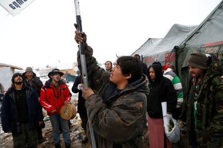 Oscar High Elk, 26, of the Cheyenne River Sioux Tribe, takes down a tribal flag as he and other members of the tribe prepare to evacuate from the main opposition camp against the Dakota Access oil pipeline near Cannon Ball, North Dakota, U.S., February 22, 2017. REUTERS/Terray Sylvester