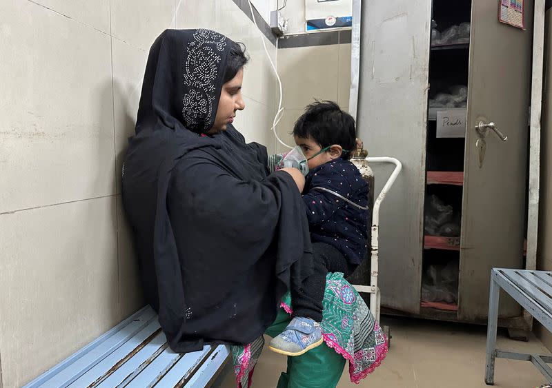 Shazma Qadeer holds a breathing mask for her one-year-old daughter Inaaya at Sir Ganga Ram hospital in Lahore