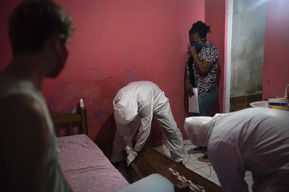 Eliete das Graças (arriba a la derecha) llora mientras operarios de SOS Funeral, con trajes de protección, cierran el ataúd de su padre, Edgar Silva, durante la pandemia del coronavirus en Manaos, Brasil, el 12 de mayo de 2020. Según das Graças, su padre tenía Alzheimer y murió en su casa tras dos días con fiebre y problemas respiratorios. (AP Foto/Felipe Dana)