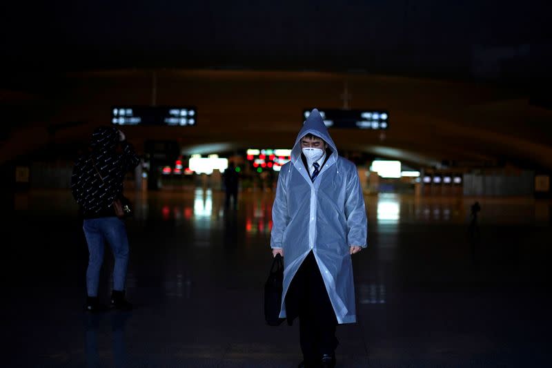 A man wearing a face mask and a plastic raincoat is seen at a railway station of Wuhan on the first day of inbound train services resumed following the novel coronavirus disease (COVID-19) outbreak, in Wuhan