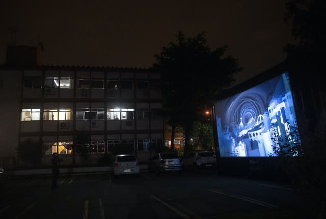 People watch a film on a giant screen through the windows of their homes in Rio de Janeiro, Brazil