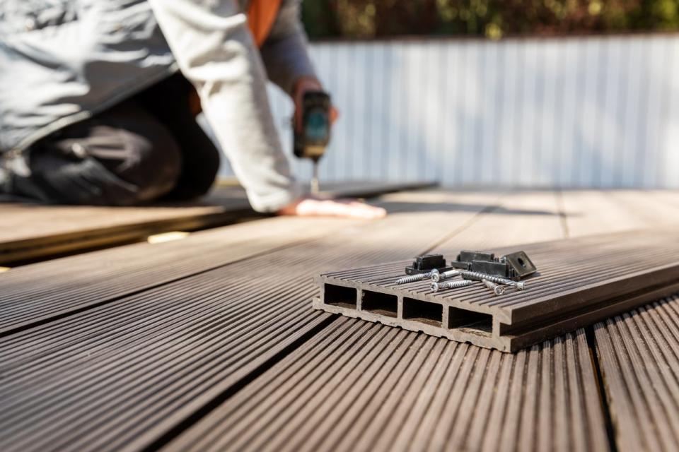 Worker installing wood-look composite decking boards.
