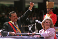 President Hugo Chavez salutes the crowd next to his wife Marisabel Chavez during a military parade commemorating the seventh anniversary of his failed 1992 coup in Caracas, Venezuela, 1999. He was elected President of Venezuela in 1998. He won lifelong support from the poor and was an inspiration for the South American left. He nationalised the country's oil reserves and funnelled money into programmes to help the poor, providing them with ample health care services, homes and work. But in doing so he alienated the middle class - whom he called 'esqualidos' (the weak ones) (AP Photo/Douglas Engle)