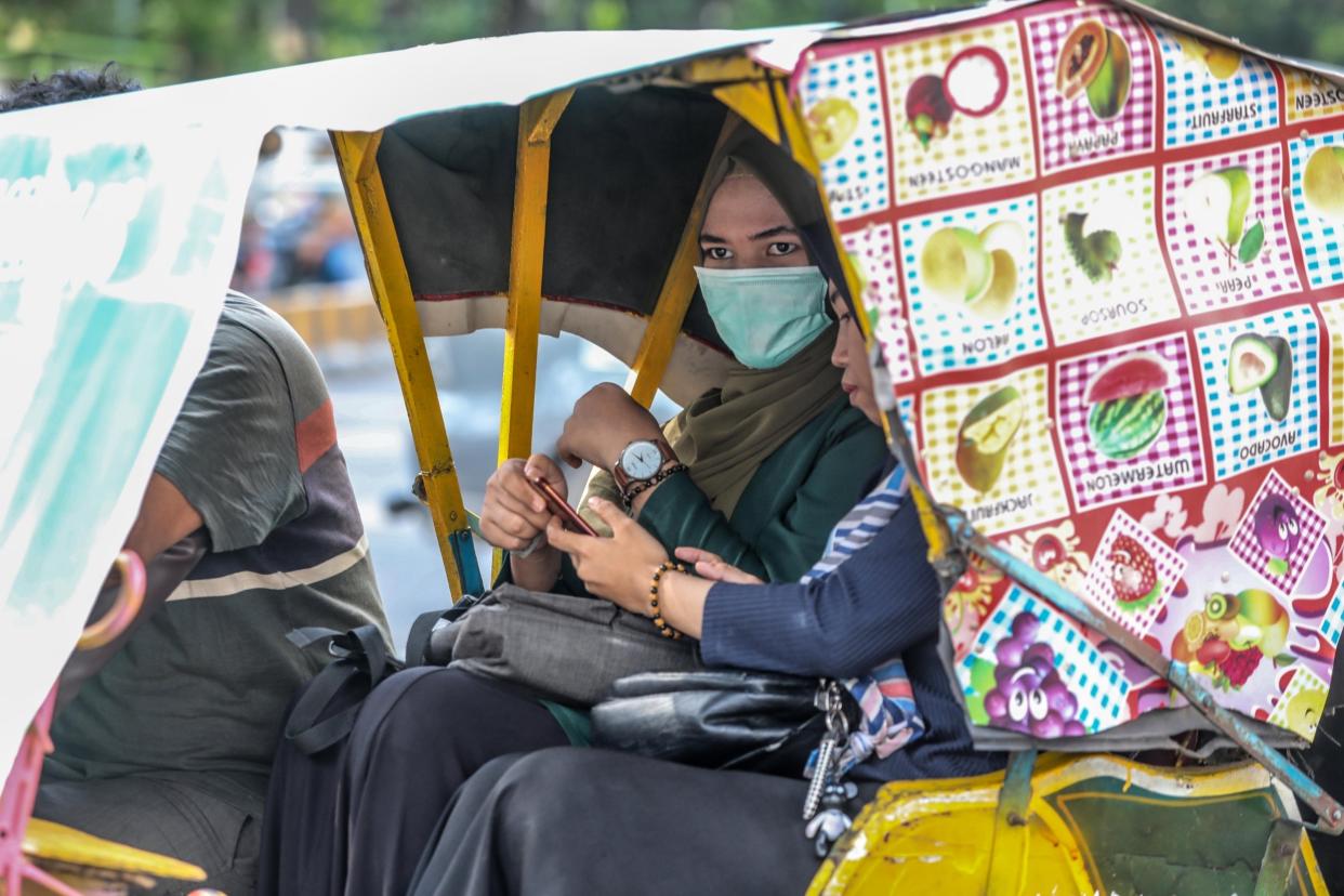 A woman wears a protective face mask as she rides on a padycab in Medan, Indonesia: EPA