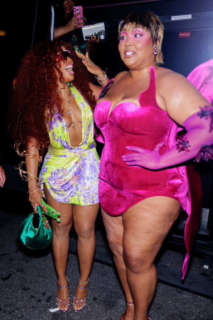 Two women in stylish outfits laughing together at an event