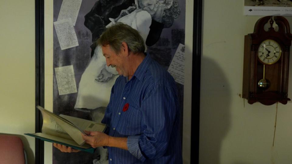 Dr. Stephen Davies in his office at Vancouver Island University, browsing a binder of letters and images from soldiers from the World Wars. 