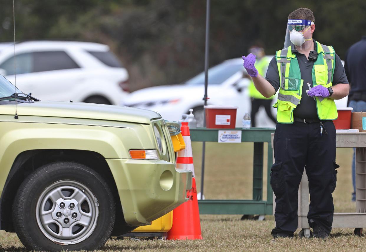 A health worker directs a vehicle before administering a COVID-19 vaccine to one of about 300 people to get vaccinated on Wednesday, Dec. 30, 2020, at the Manatee County Public Safety Center in Bradenton, Fla.