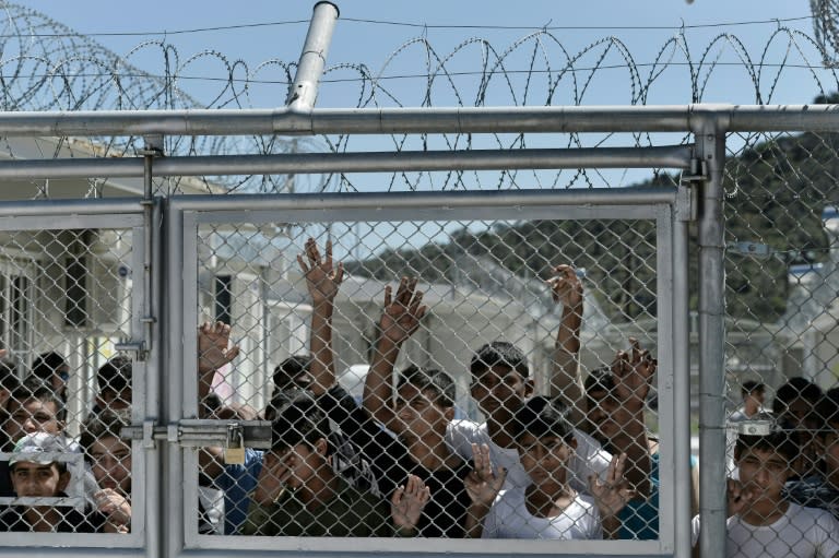 Young migrants and refugees stand at a fence of the Moria detention centre on the Greek island of Lesbos