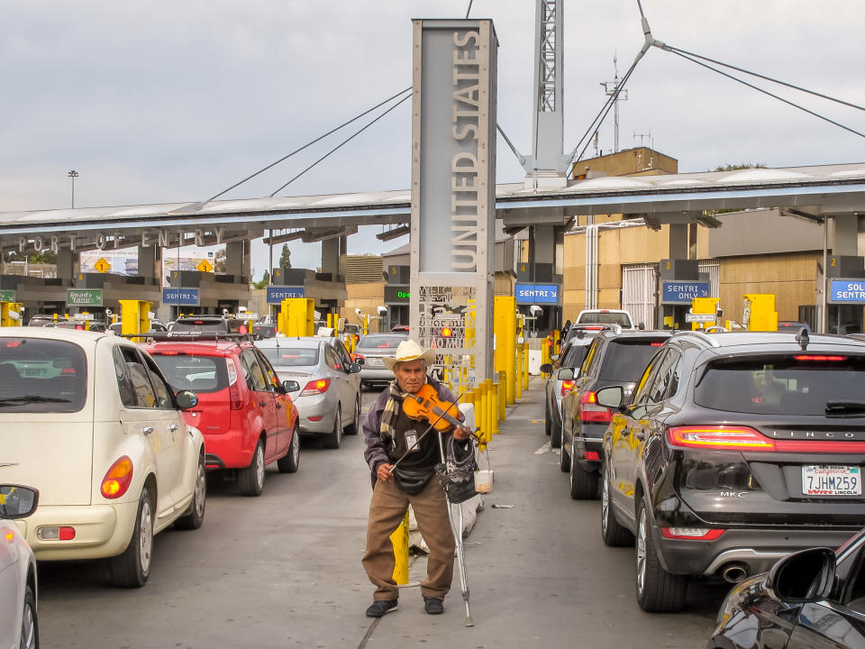 At the border station between Tijuana and San Ysidro, a man plays his violin amid dozens of cars lined up on the Mexican side waiting to cross the border between Mexico and the United States.  Many Mexicans cross this border daily to work in the United States.  Photo: Getty Images. 