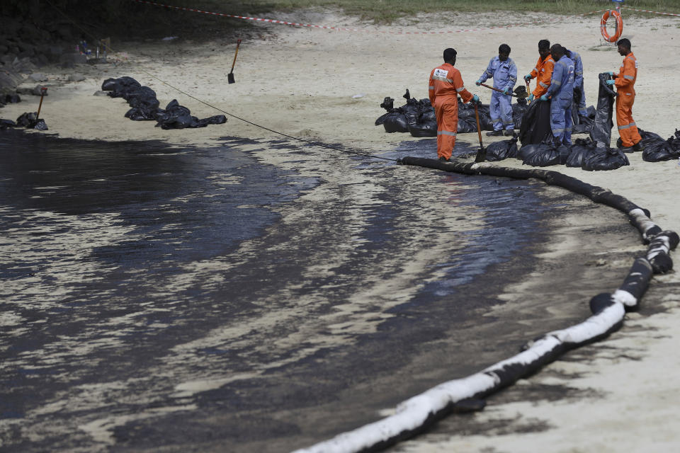 Operarios limpian una mancha de crudo en la zona de la playa de Tanjong, en Sentosa, Singapur, el 16 de junio de 2024, luego de un vertido de crudo desde un barco. (AP Foto/Suhaimi Abdullah)