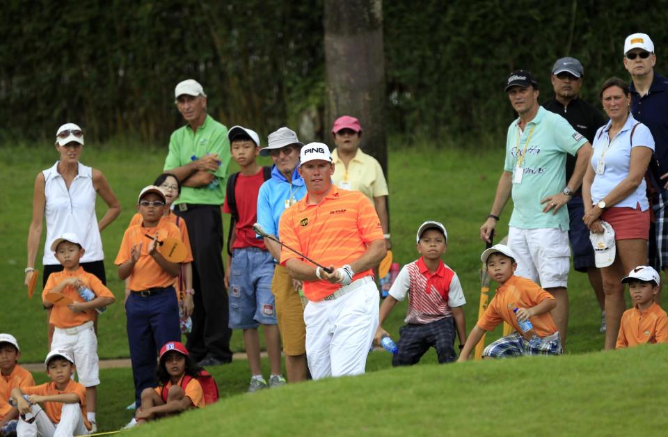 Lee Westwood, center, of England watches his shot on the fifth hole during the third round of the Malaysian Open golf tournament at Kuala Lumpur Golf and Country Club in Kuala Lumpur, Malaysia, Saturday, April 19, 2014. (AP Photo/Lai Seng Sin)